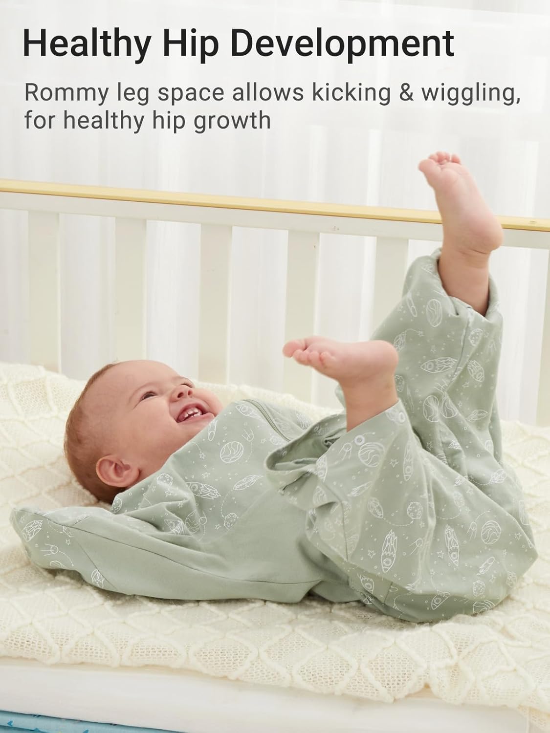 Baby in pale green cotton swaddle sack, roomy legs promote healthy hip growth, 3-6 months.