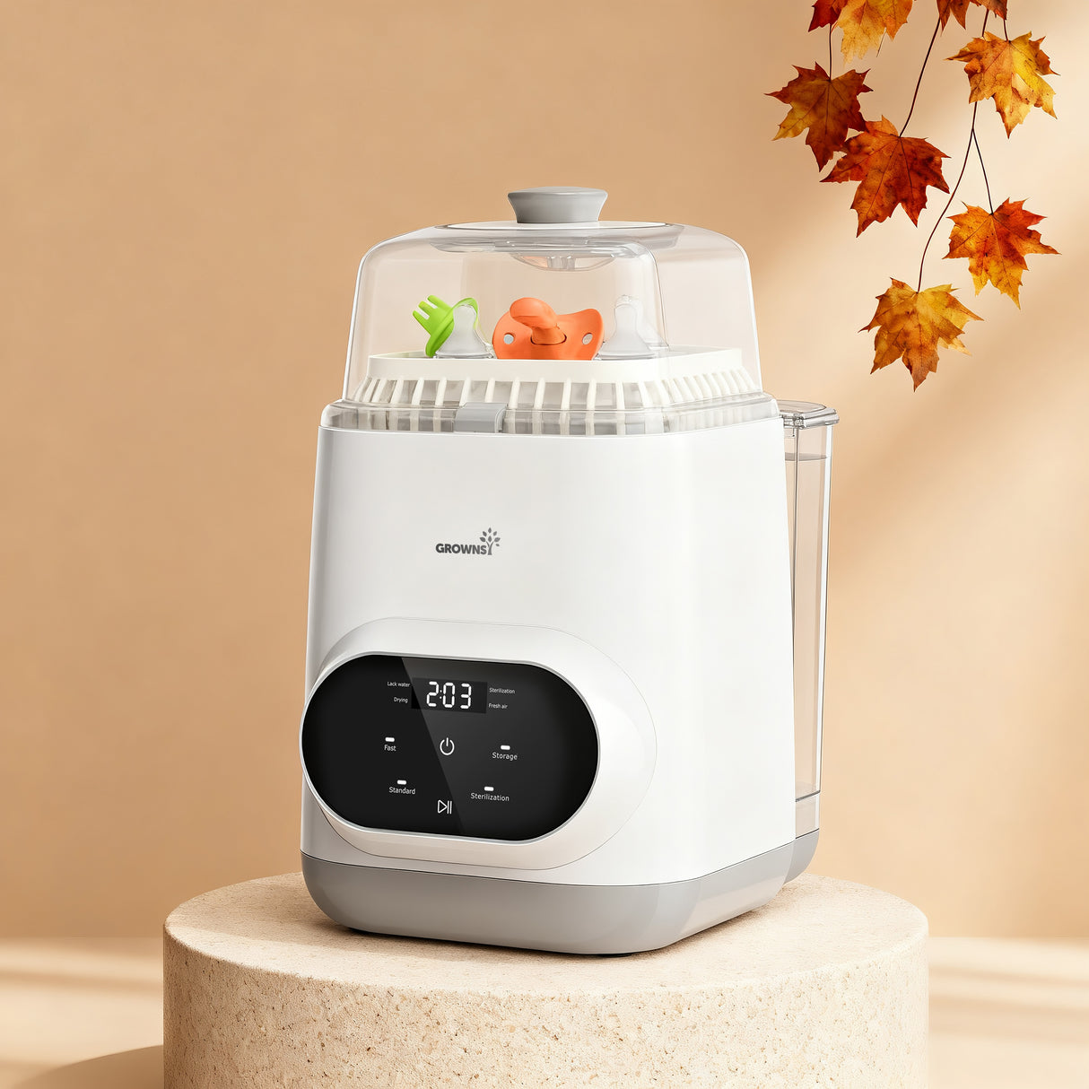 White Grownsy EaseClean bottle washer with clear lid and digital display, holding green nipple and orange pacifier.