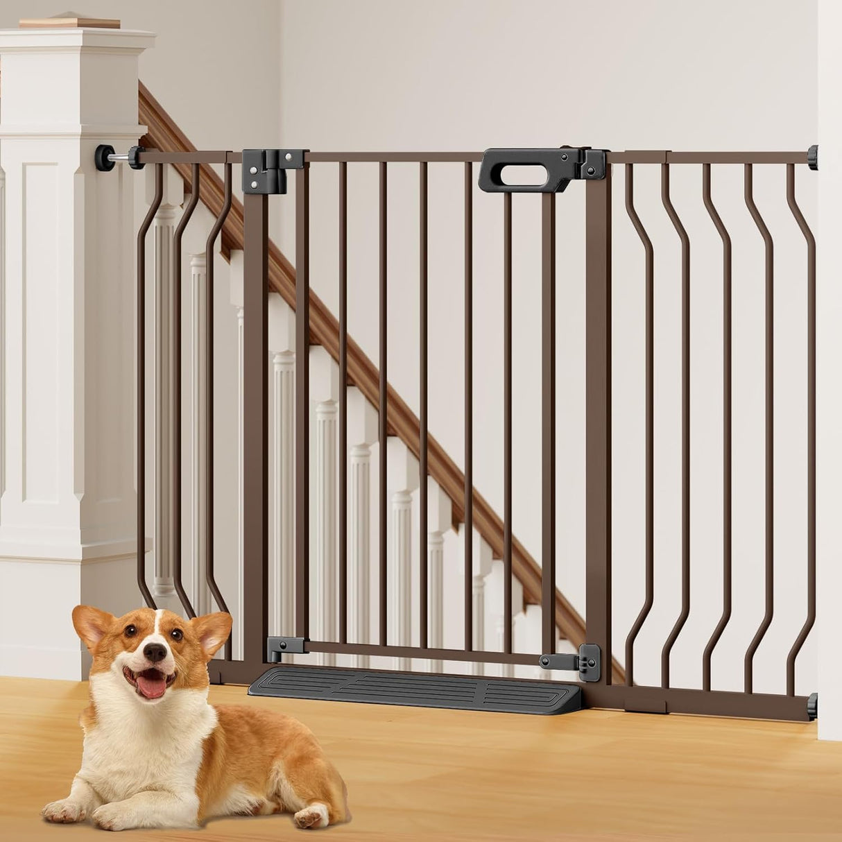 Bronze GROWNSY baby gate with anti-stumble pedal installed at bottom of wooden stairs, Corgi dog on floor.