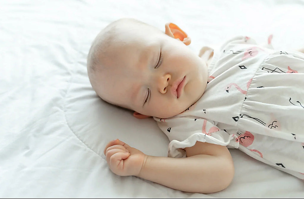 A 6-month-old baby sleeping on a bed