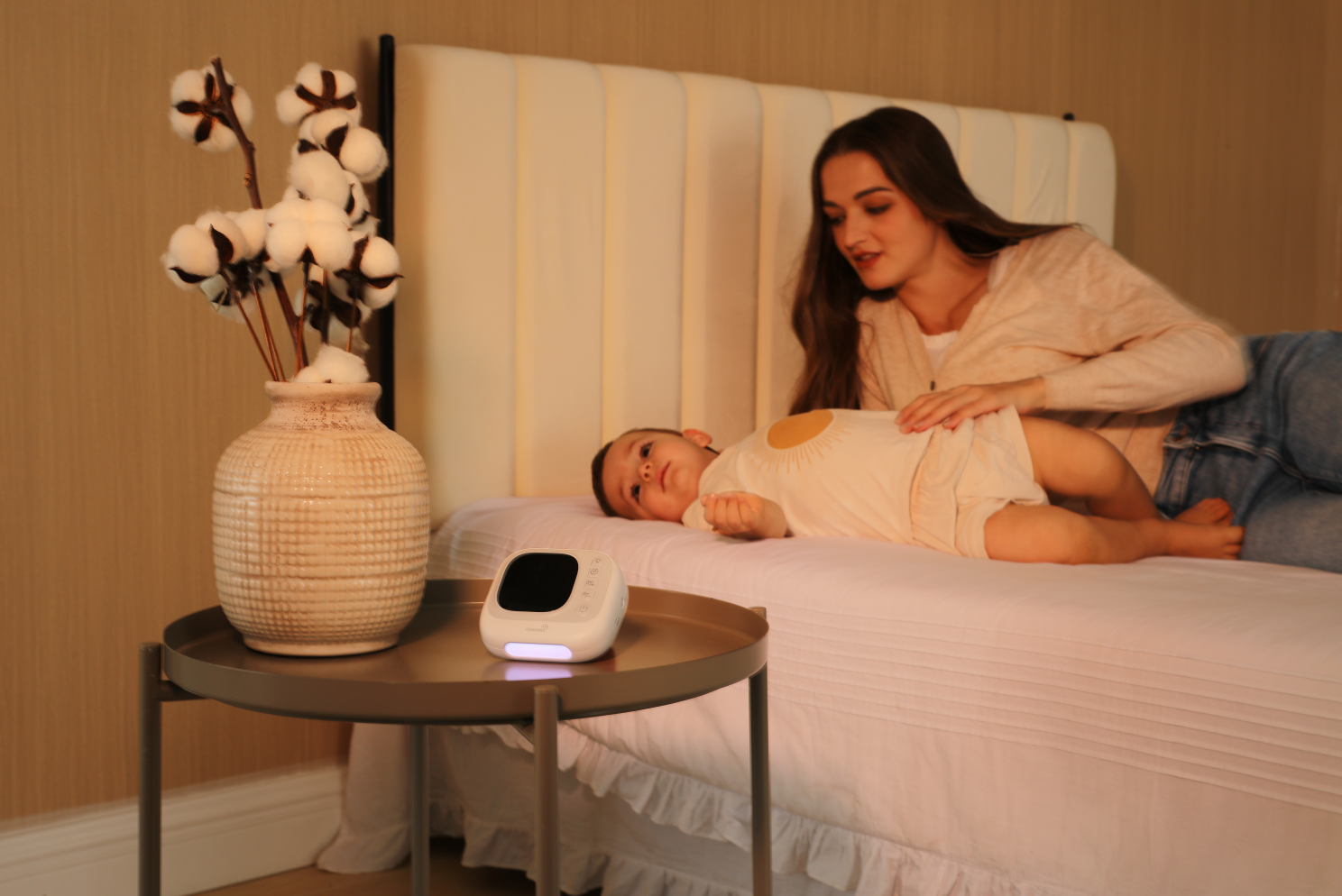 Mother with baby on bed near GROWNSY baby care device and cotton vase