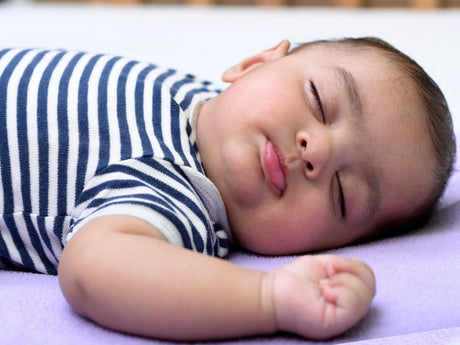 Peaceful baby sleeping on purple blanket in striped onesie at GROWNSY baby care store