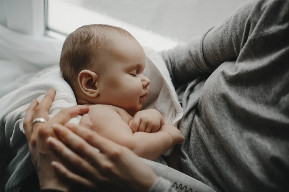 Sleeping baby held close against a parent’s chest.