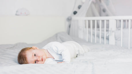 A 11 month old baby laying in bed for a day nap