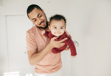 Smiling father holds happy baby in red outfit, GROWNSY baby care lifestyle image