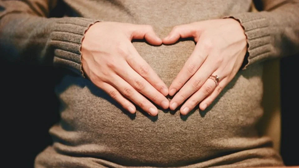 Pregnant woman cradling her belly before an exercise ball pregnancy workout.