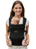 Grownsy Easy-Breezy black baby carrier with padded straps shown on a smiling woman with baby facing out.